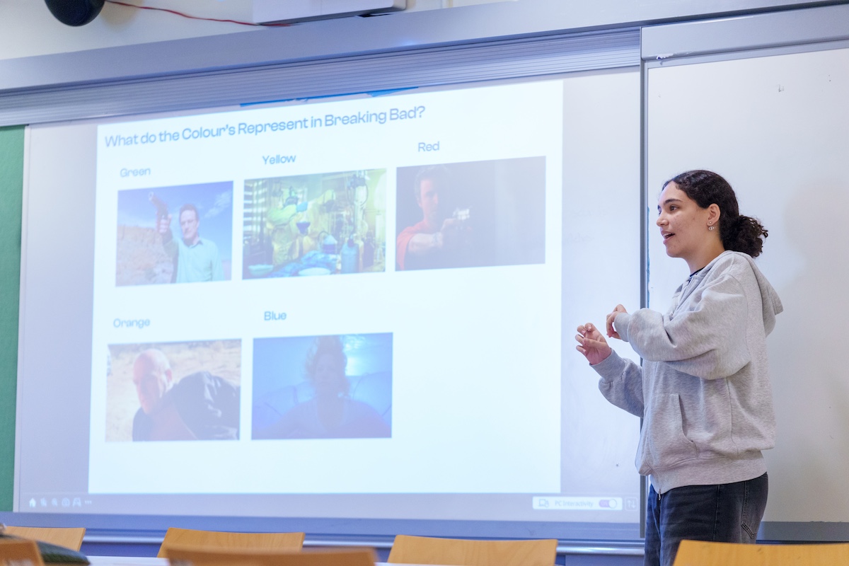 A student presents in front of a projected slide analyzing color symbolism in the TV series Breaking Bad.