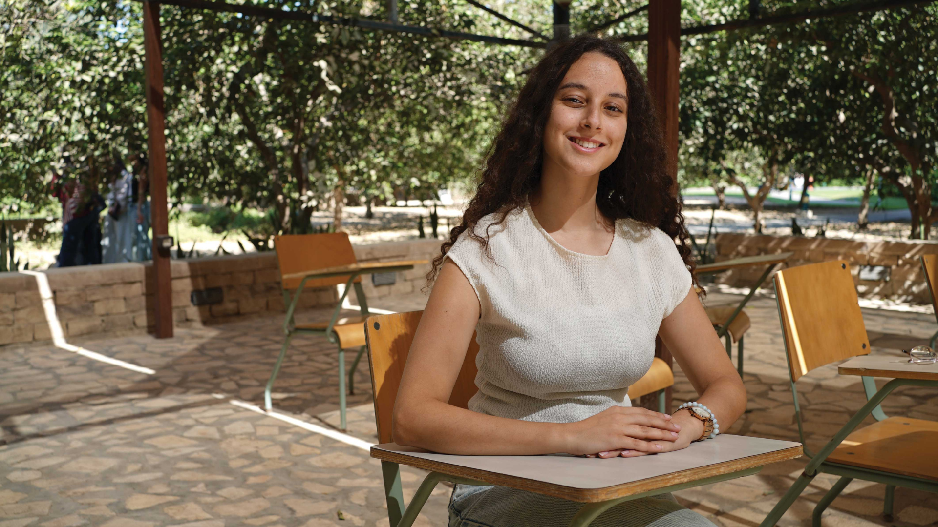 Malak Hashem sits in a chair in an outdoors classroom.