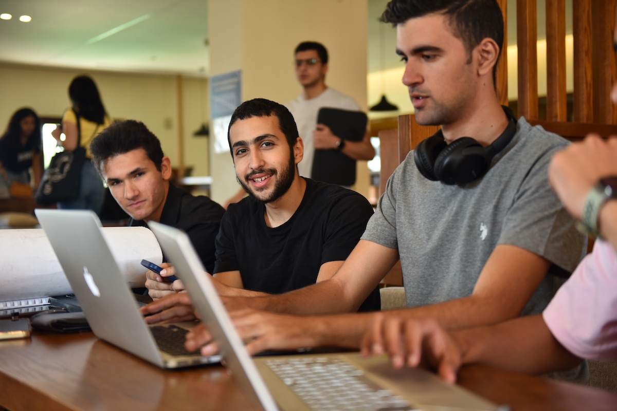 A group of students sit together using laptops while collaborating on work in a study space.