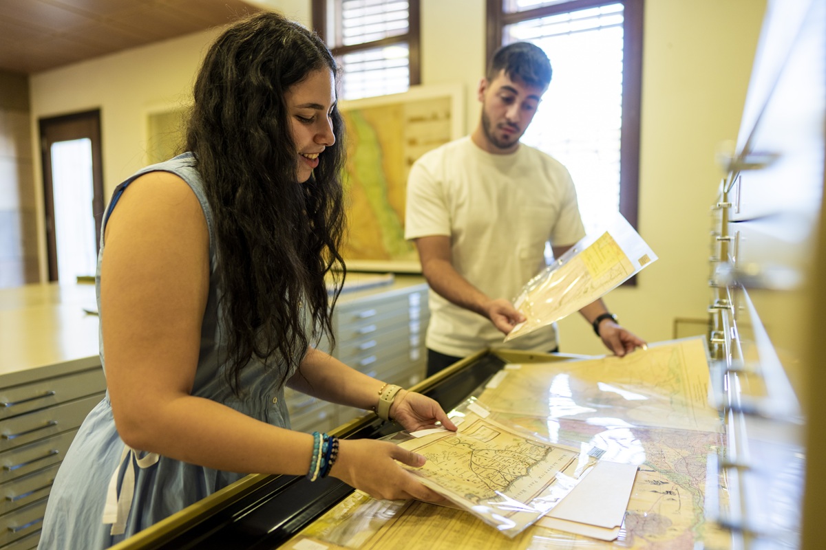 A male and female are looking at maps