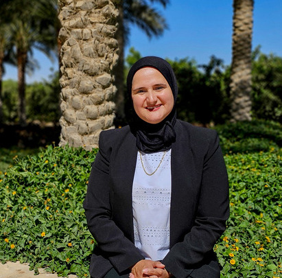 Headshot of a veiled woman smiling in an outdoor setting