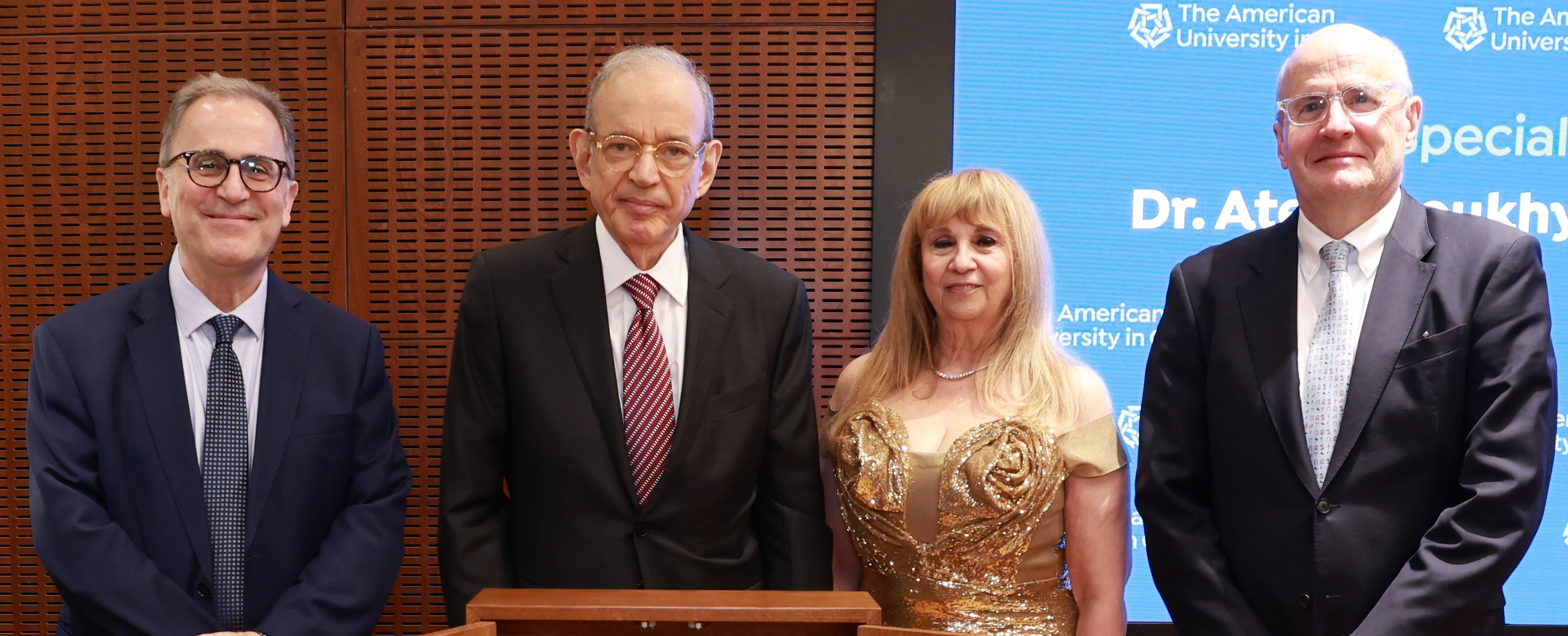 Atef Eltoukhy and his wife Fofa stand next to an AUC podium, along with AUC President Ahmad Dallal and Board of Trustees Chairman Mark Turnage