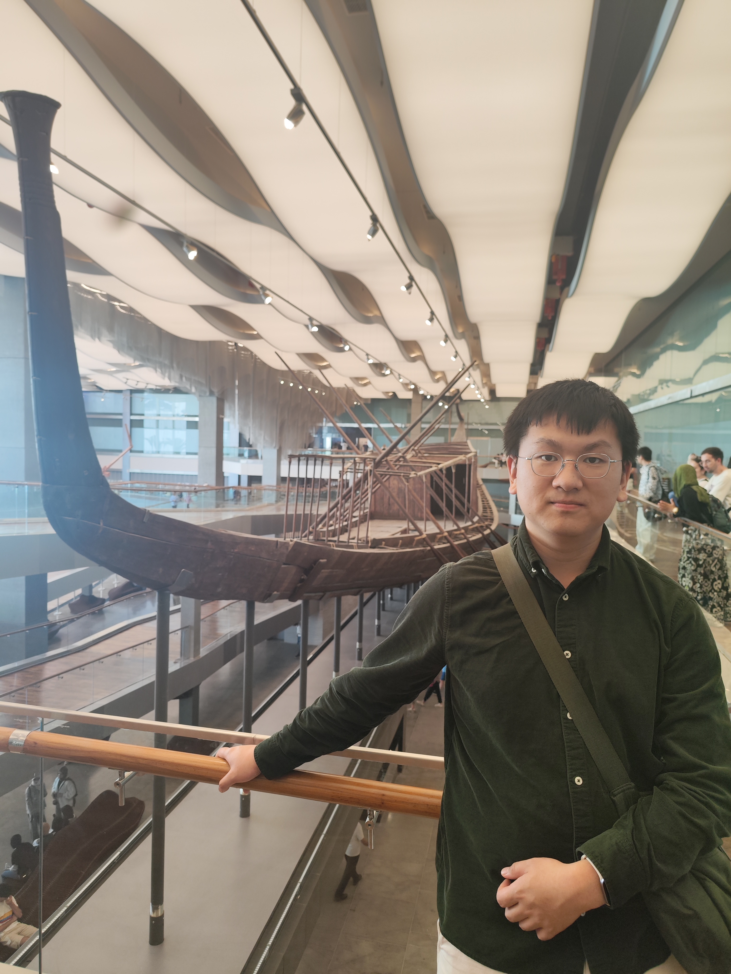 a chinese student wearing glasses with black hair and standing in a boat