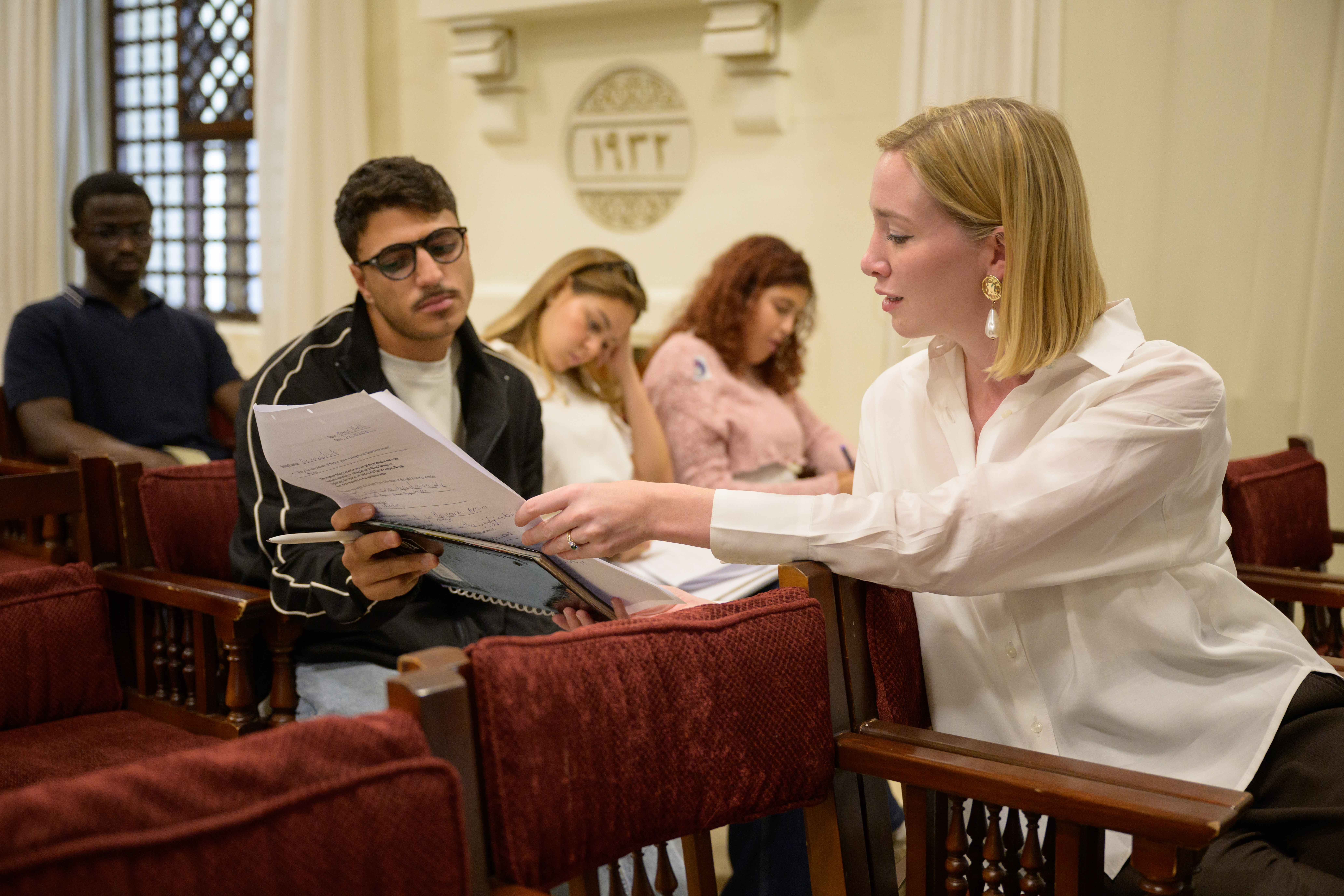 Nina Ellis in class, looking at a paper with a student
