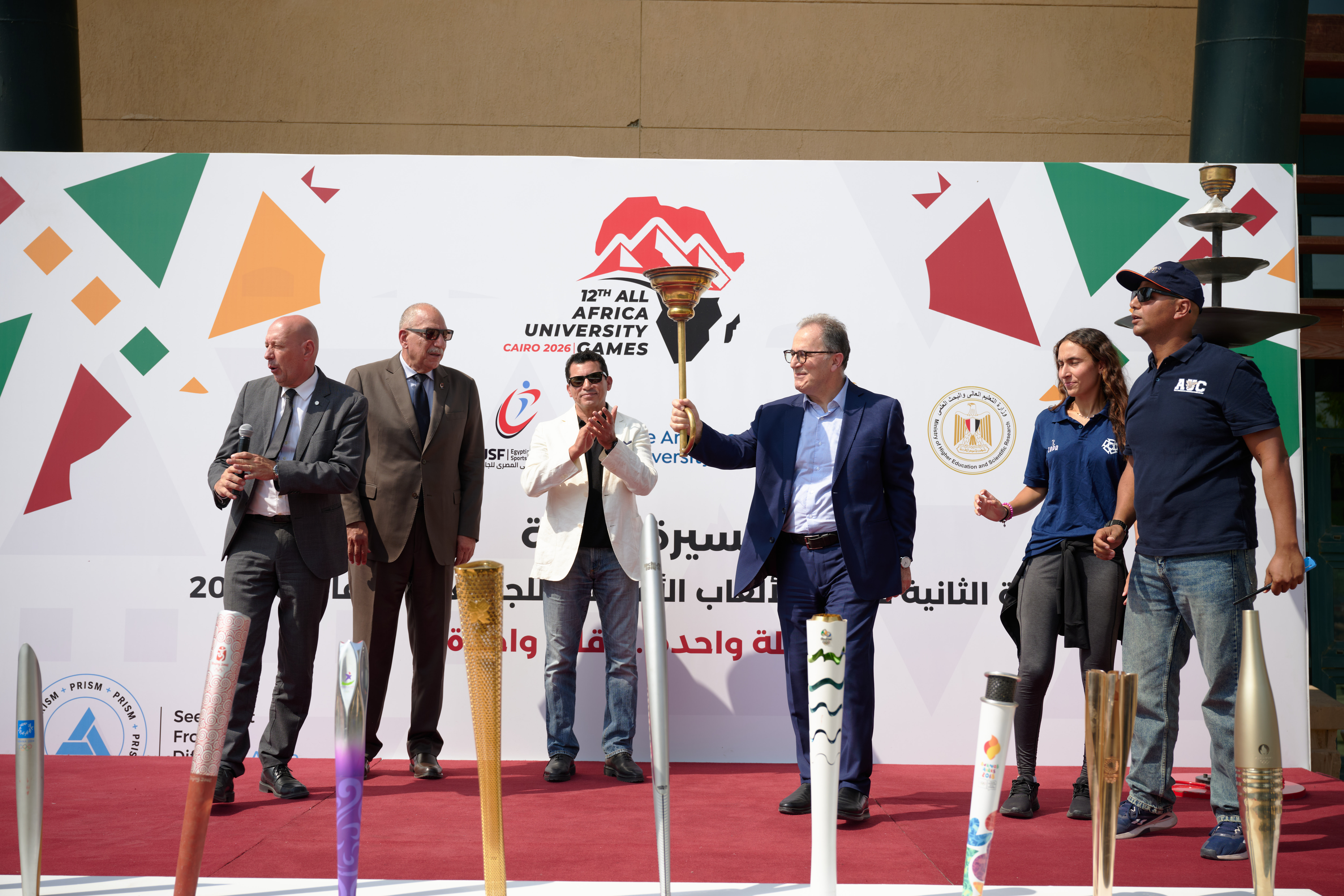 AUC President holding the torch on stage with guests