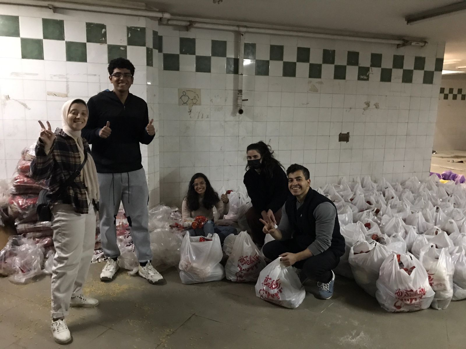 Volunteers in Action smile next to dozens of handmade Ramadan food packs