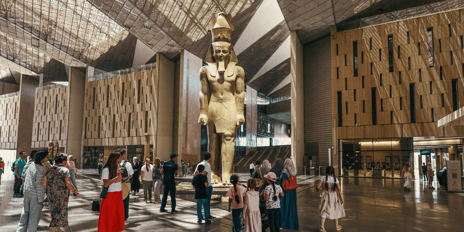 A statue of Ramses II with tourists below.