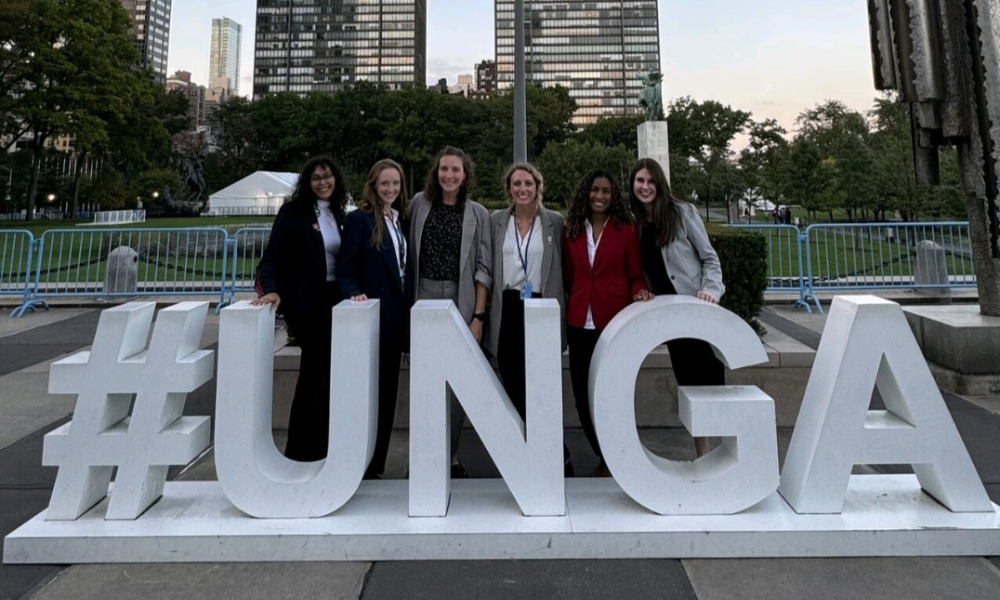 Zein Ibrahim stands with a group of five people in front of a sign which reads #UNGA