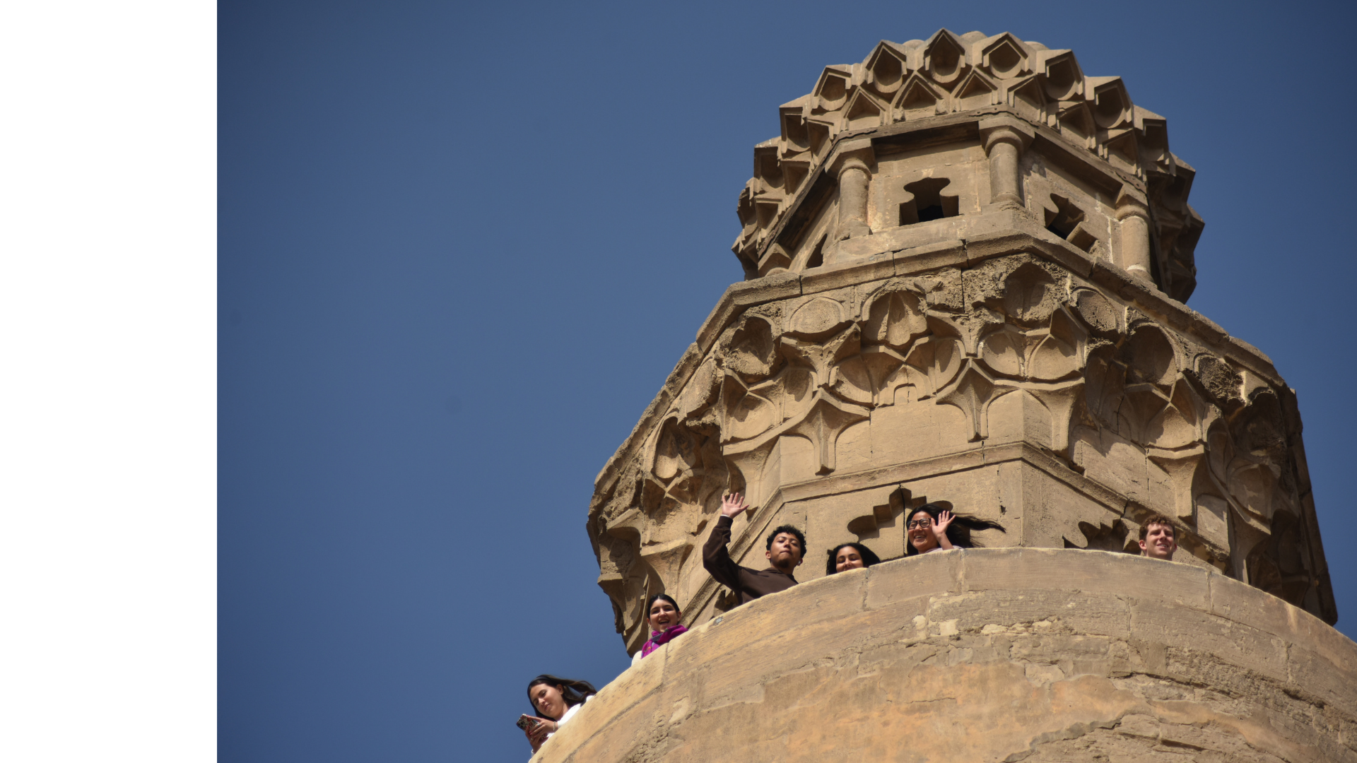 A group of students wave from an old tower