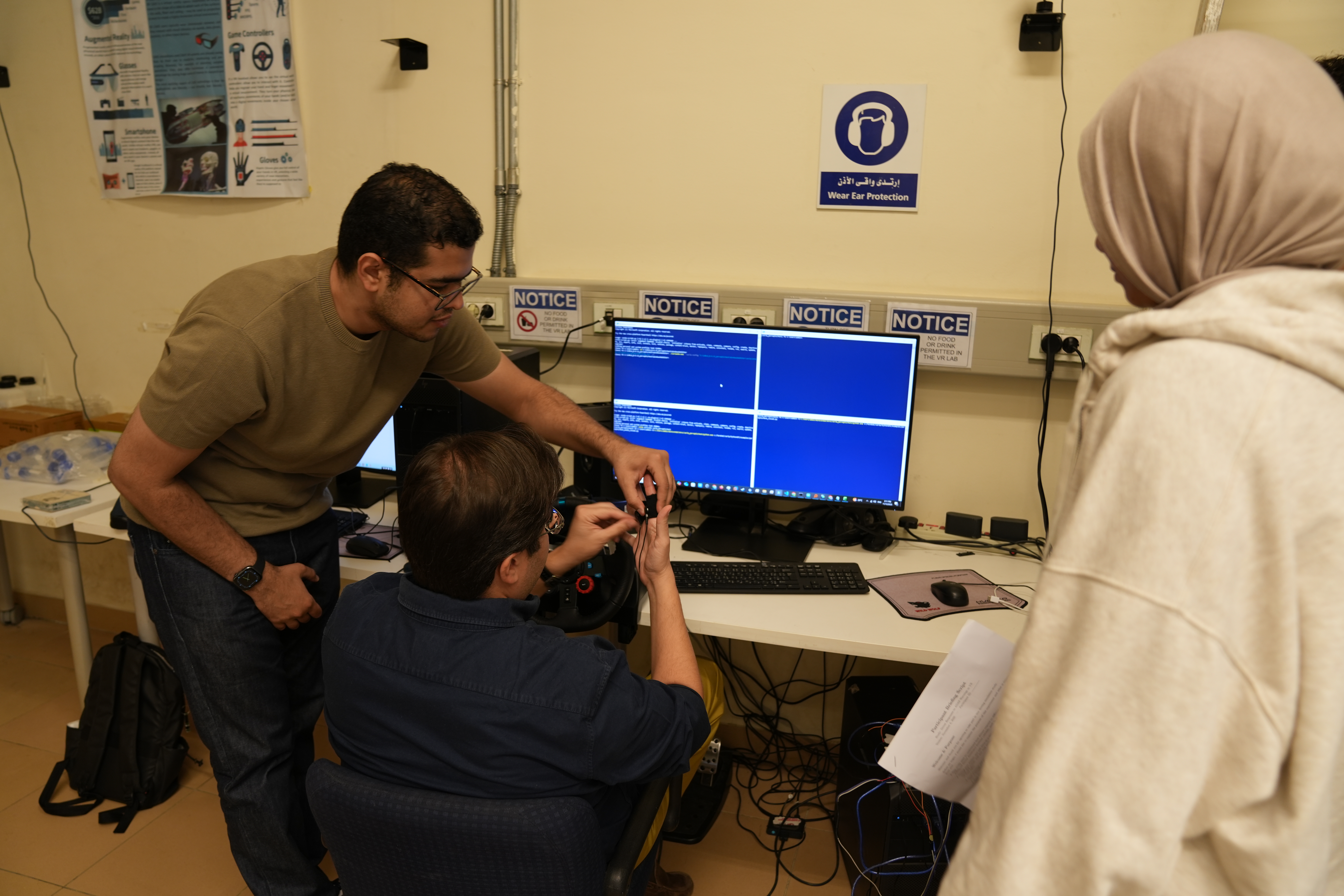 Three people work in front of a monitor displaying lines of code