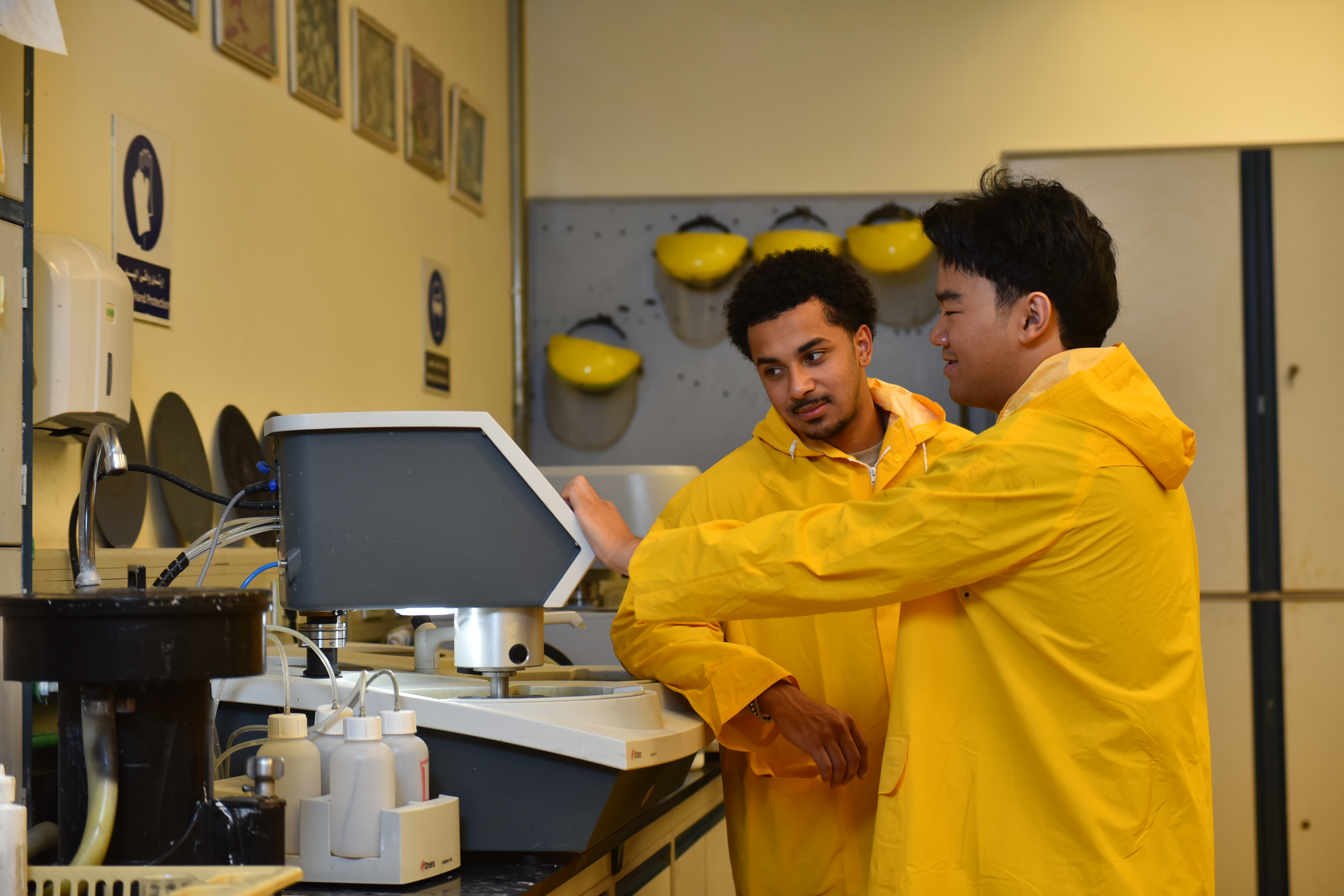 Yusef Primus and Anthony Nguyen observe a machine operating in a mechanical workshop