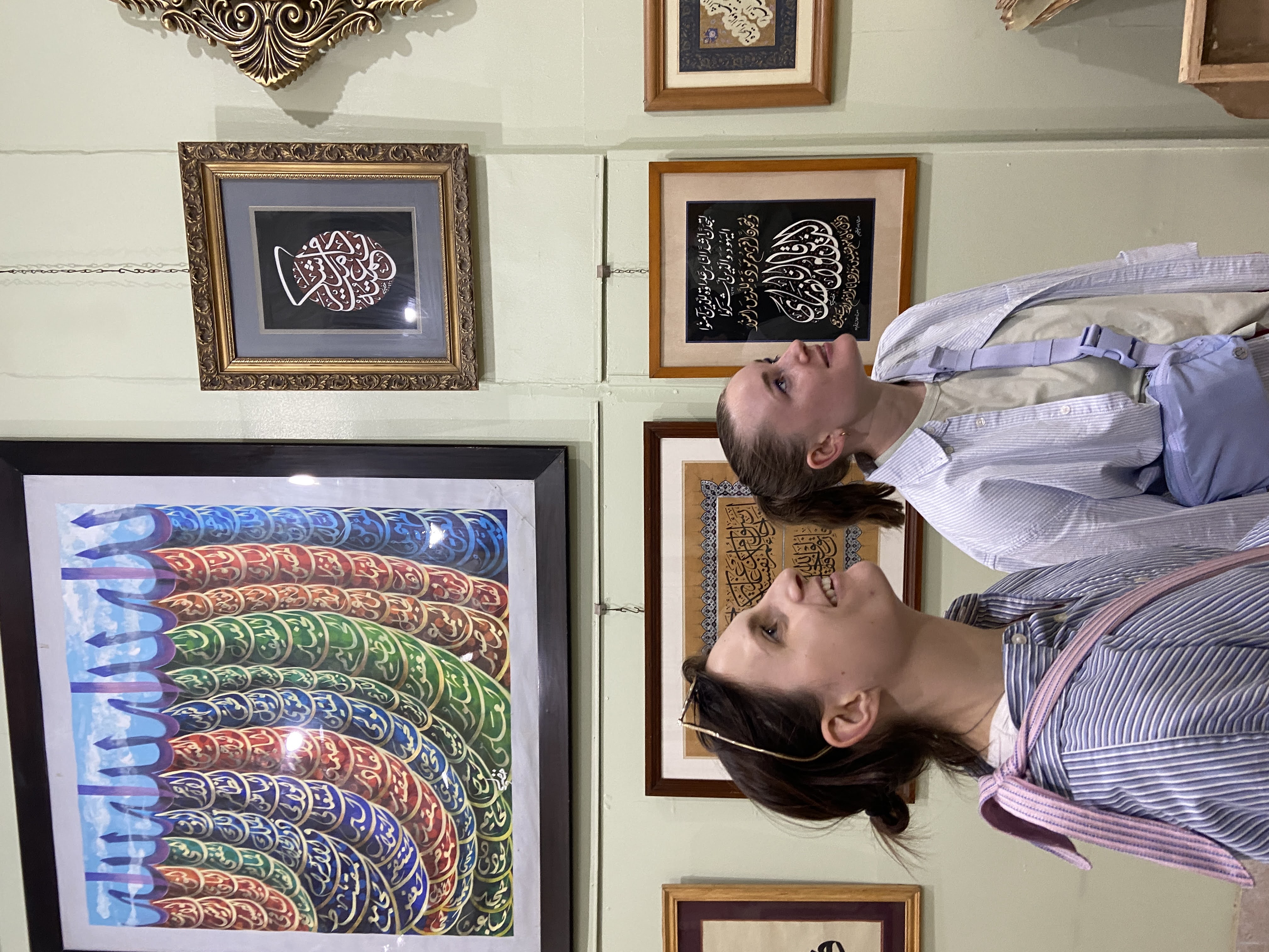 two women stand in a gallery looking at a display of Arabic calligraphy