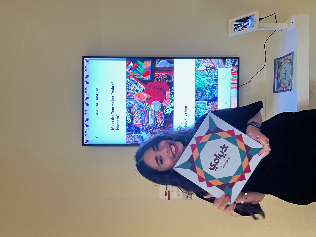 woman standing in front of a screen holding a book and smiling