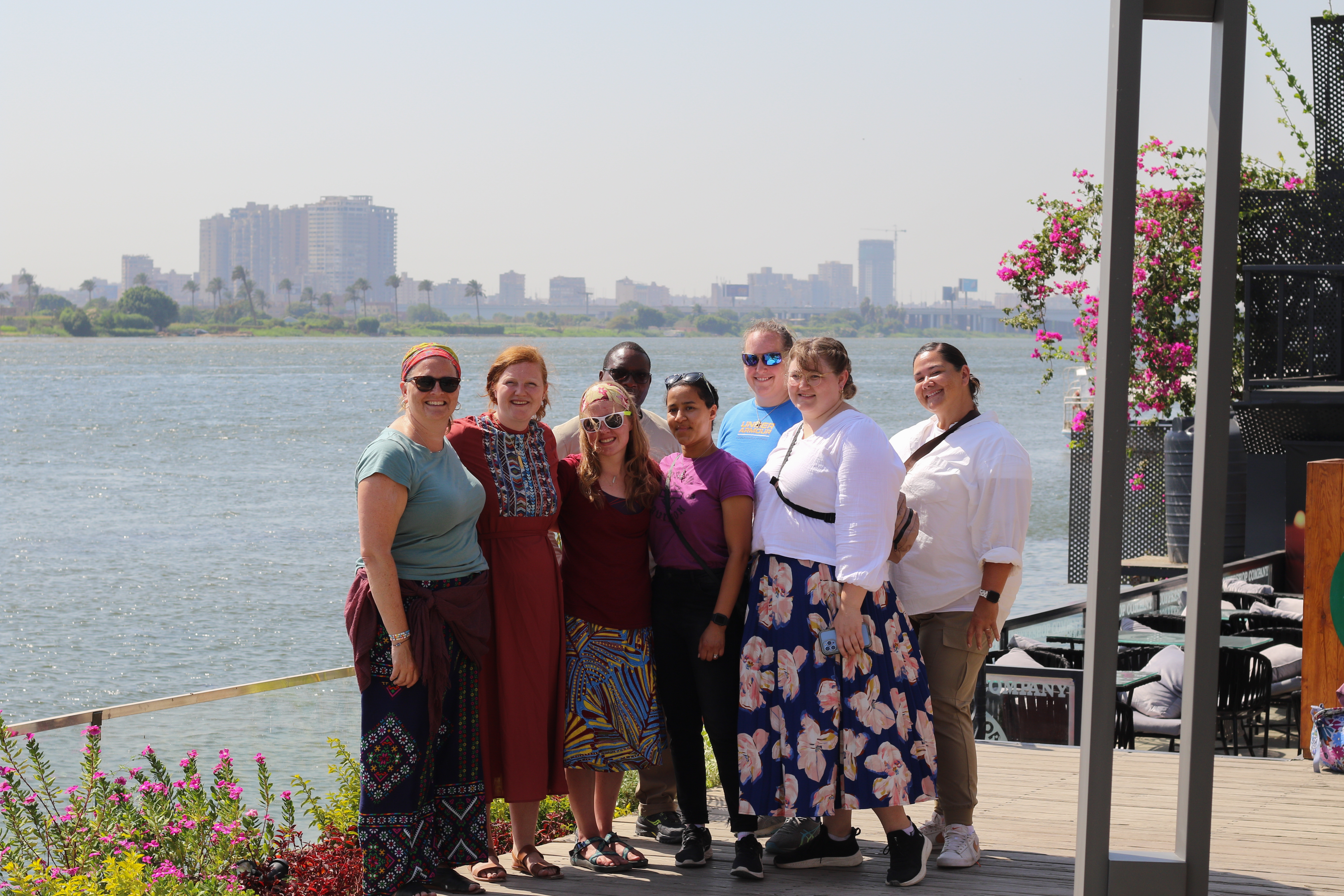 Eight people stand next to the Nile smiling