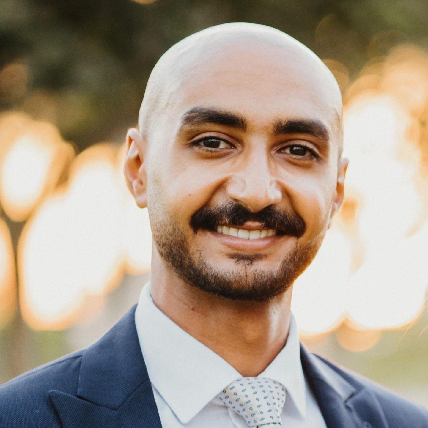 a bold man with mustache and light beard wearing a suit