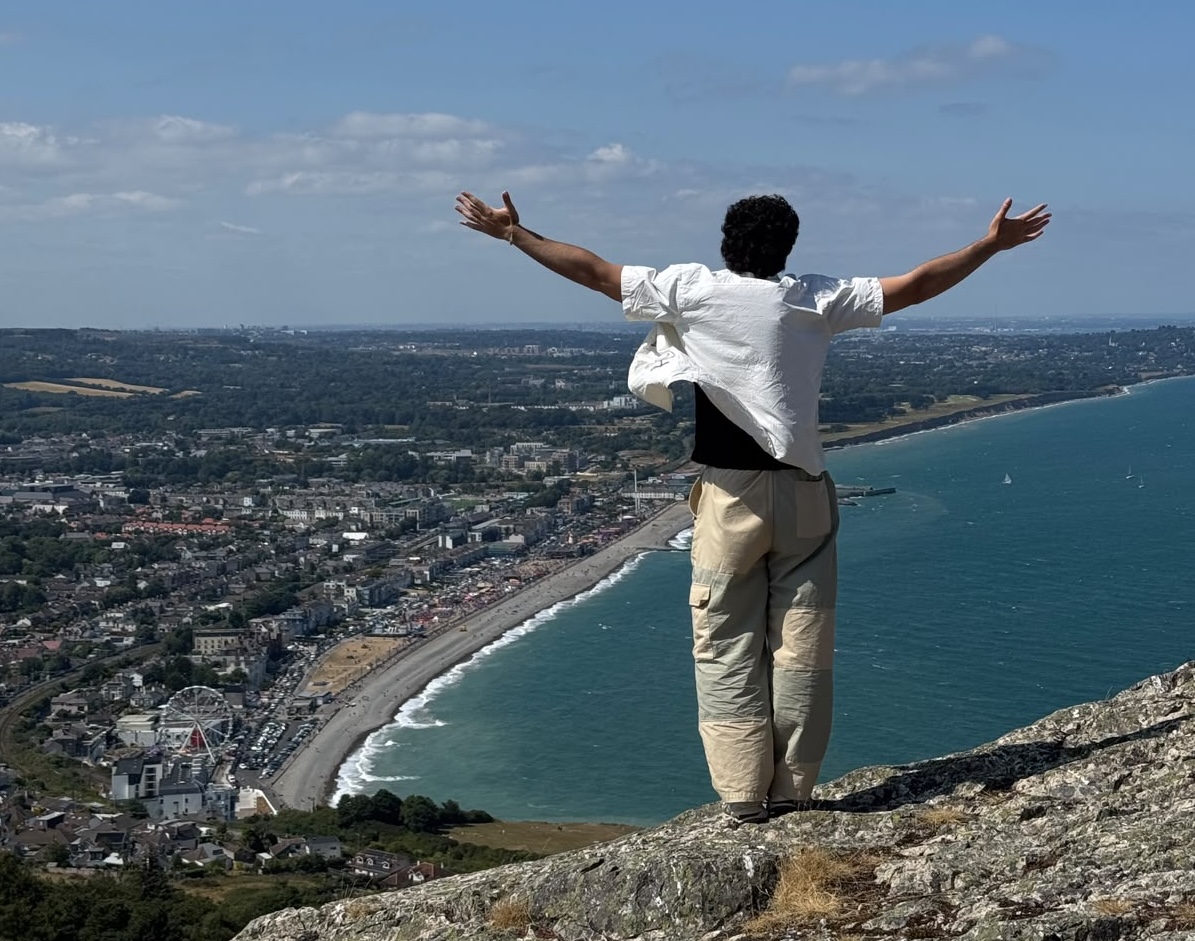 a man standing on a cliff with a view of the sea and the city