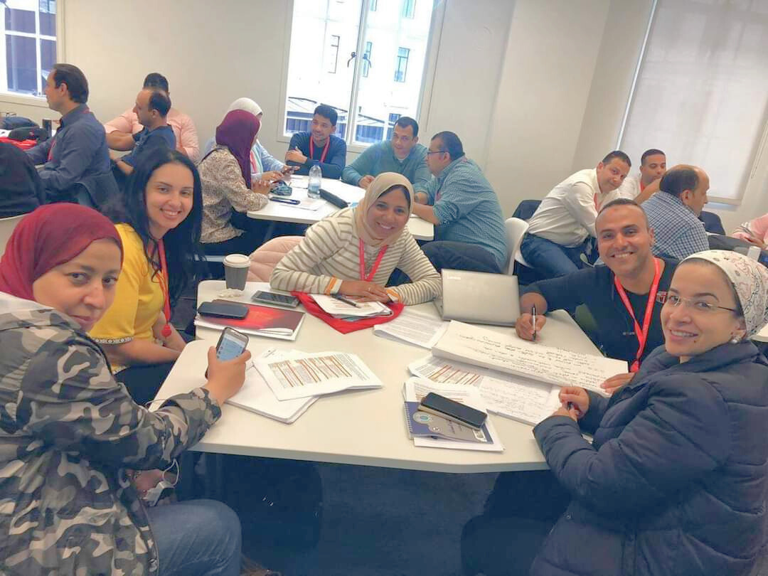 LEP participants are seated around a table, working on a task while turning and smiling at the camera.
