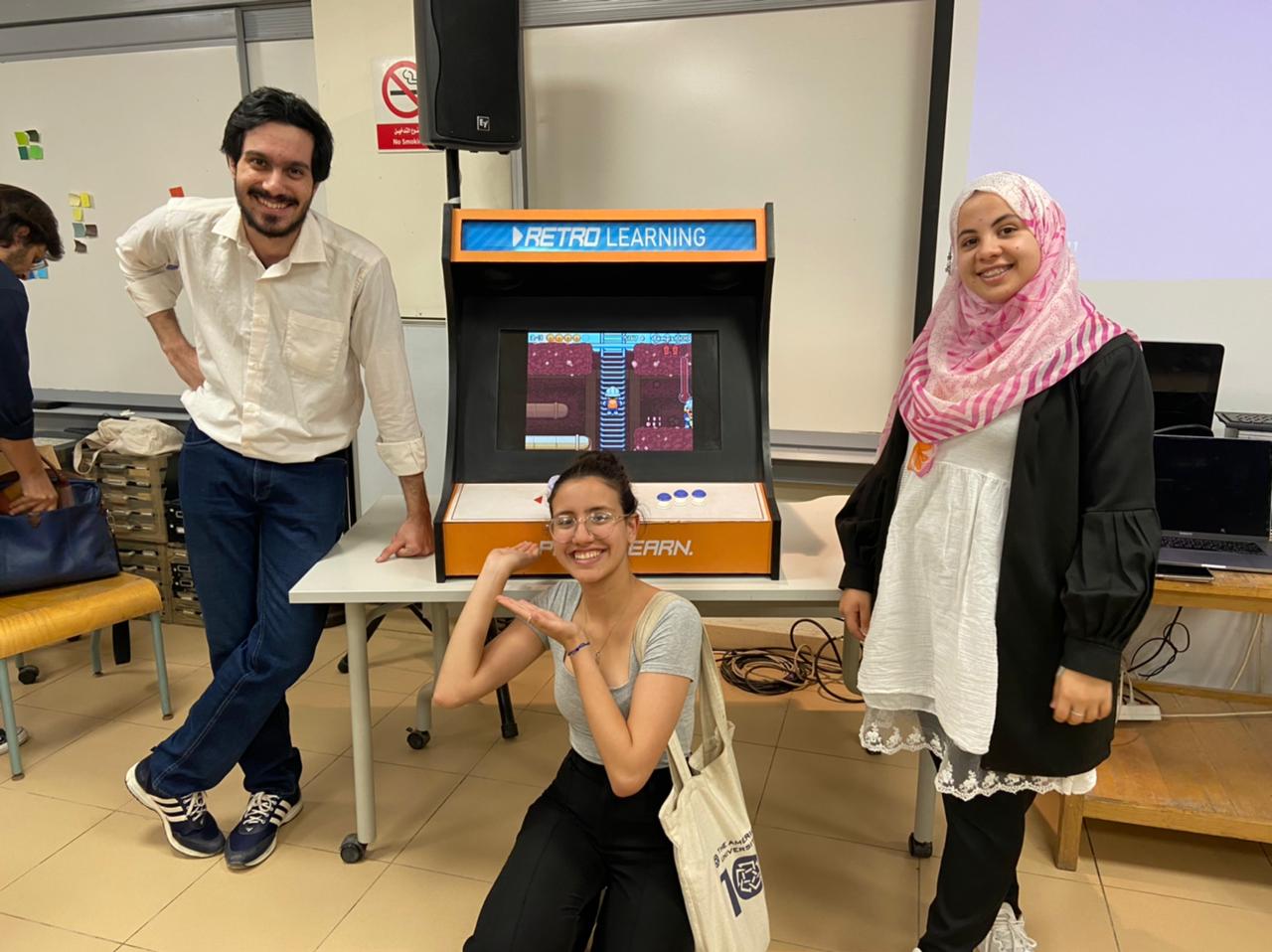 Mahmoudi and her team pose in front of the arcade machine