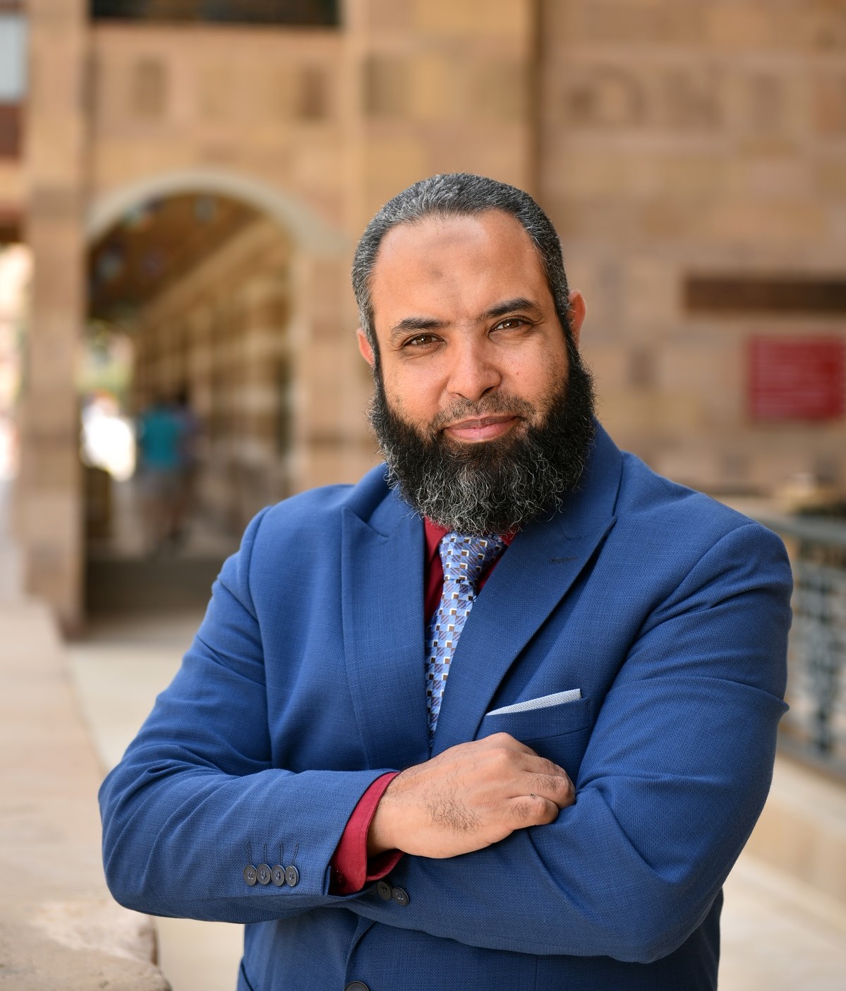 El Sawy stands with his arms crossed on campus, looking at the camera while slightly smiling. 