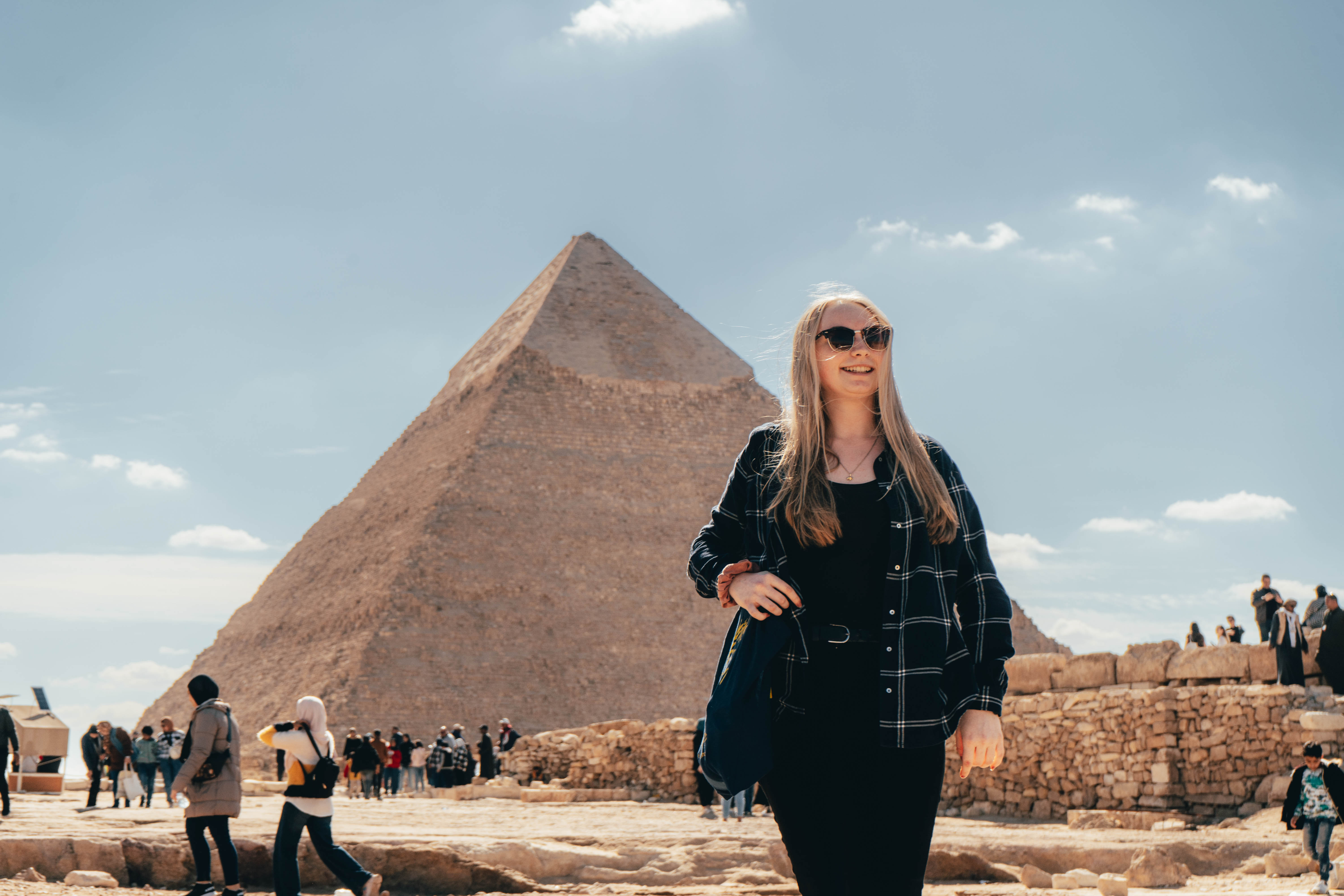 Woman smiles in front of one of the Great Pyramids