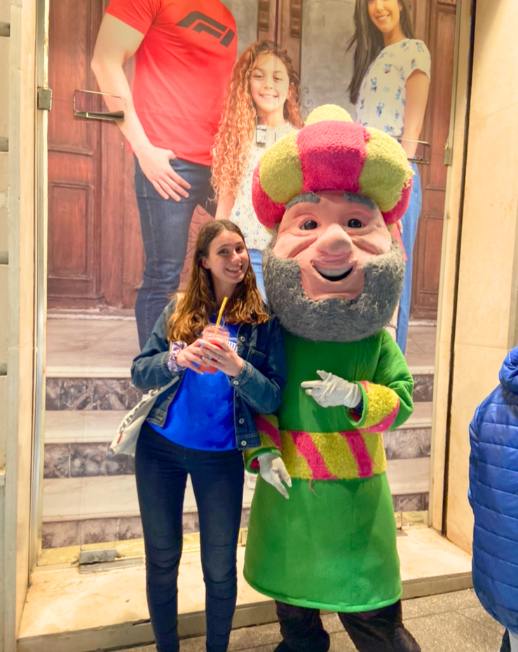 Carere smiles and stands next to a mascot of a Ramadan character near Talaat Harb, holding fresh strawberry juice.