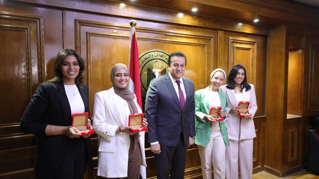 Four AUC students stand with the Minister of Higher Education, holding ministry of shield awards and smiling at the camera