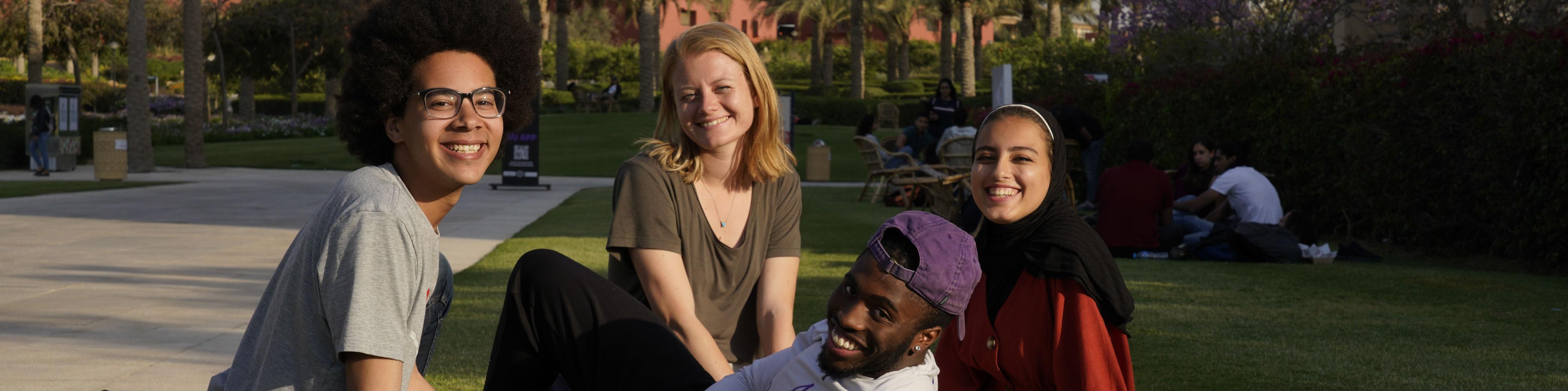 AUC international students sitting in the campus gardens. 