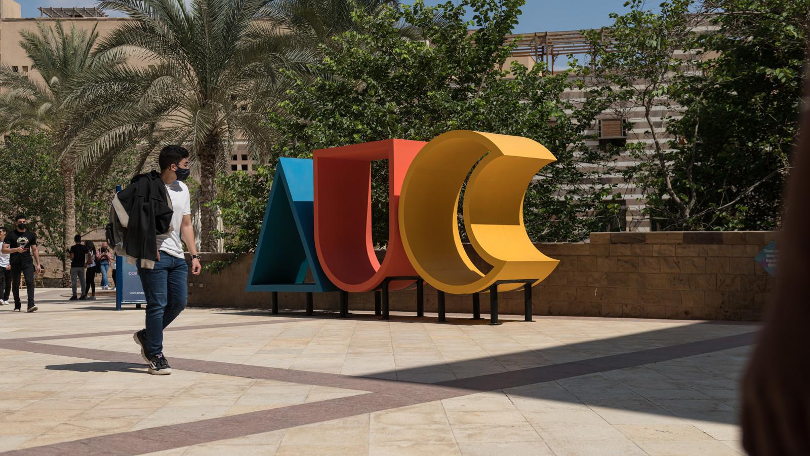Student standing in front of AUC logo