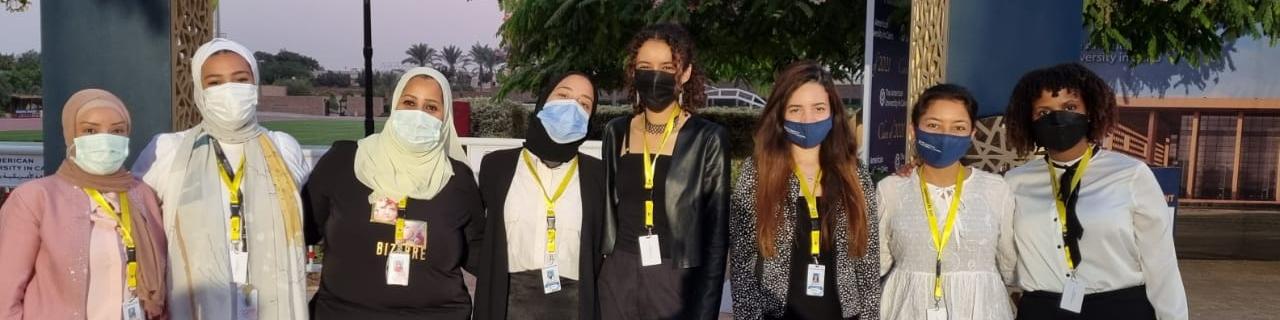 Multiple female event coordinators wearing facial masks and standing together for a picture during the graduation of the class of 2021
