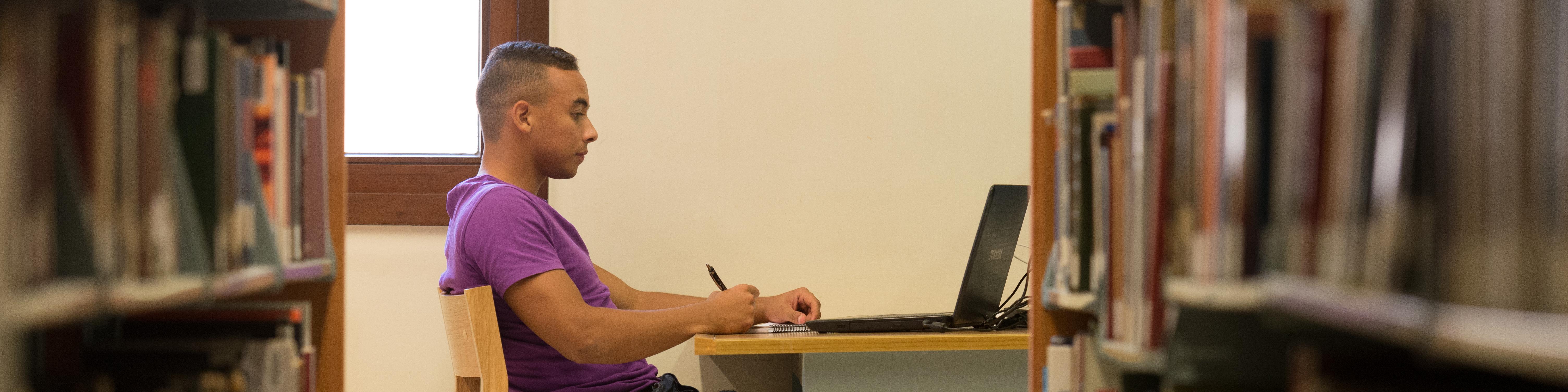 Male student sitting at a desk in the AUC main library