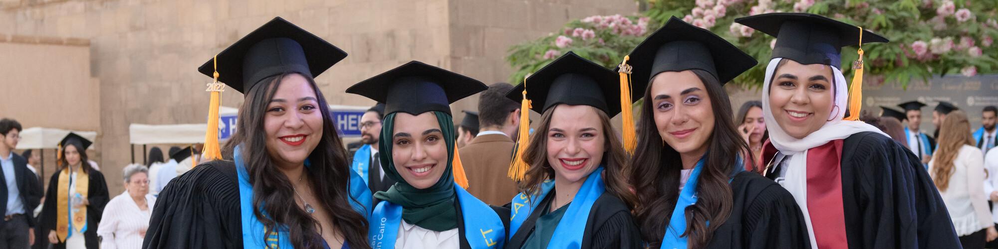group of smiling girls with cap and gown