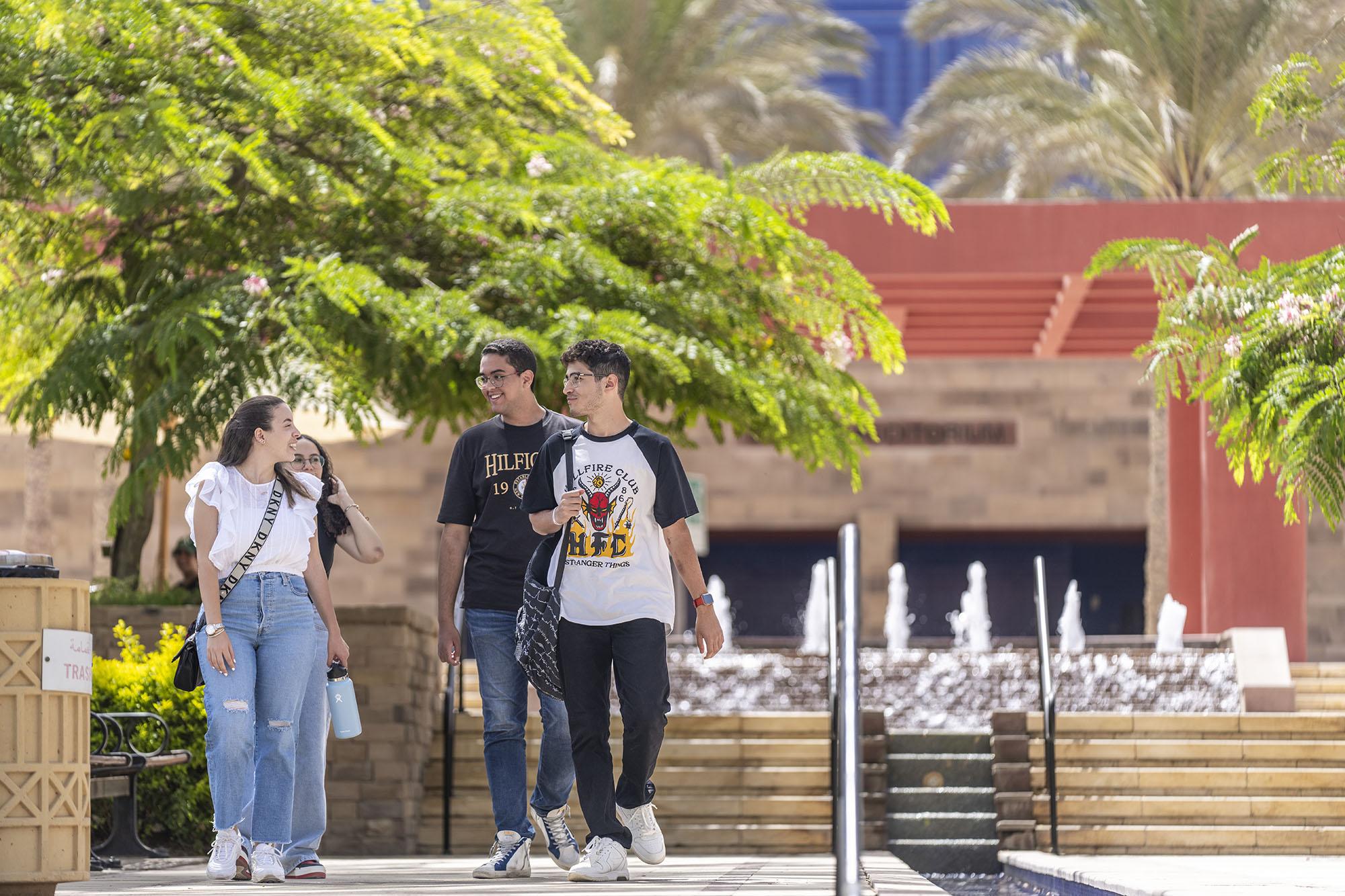 A group of girls and boys walking on campus infornt of Bassily Auditoriam