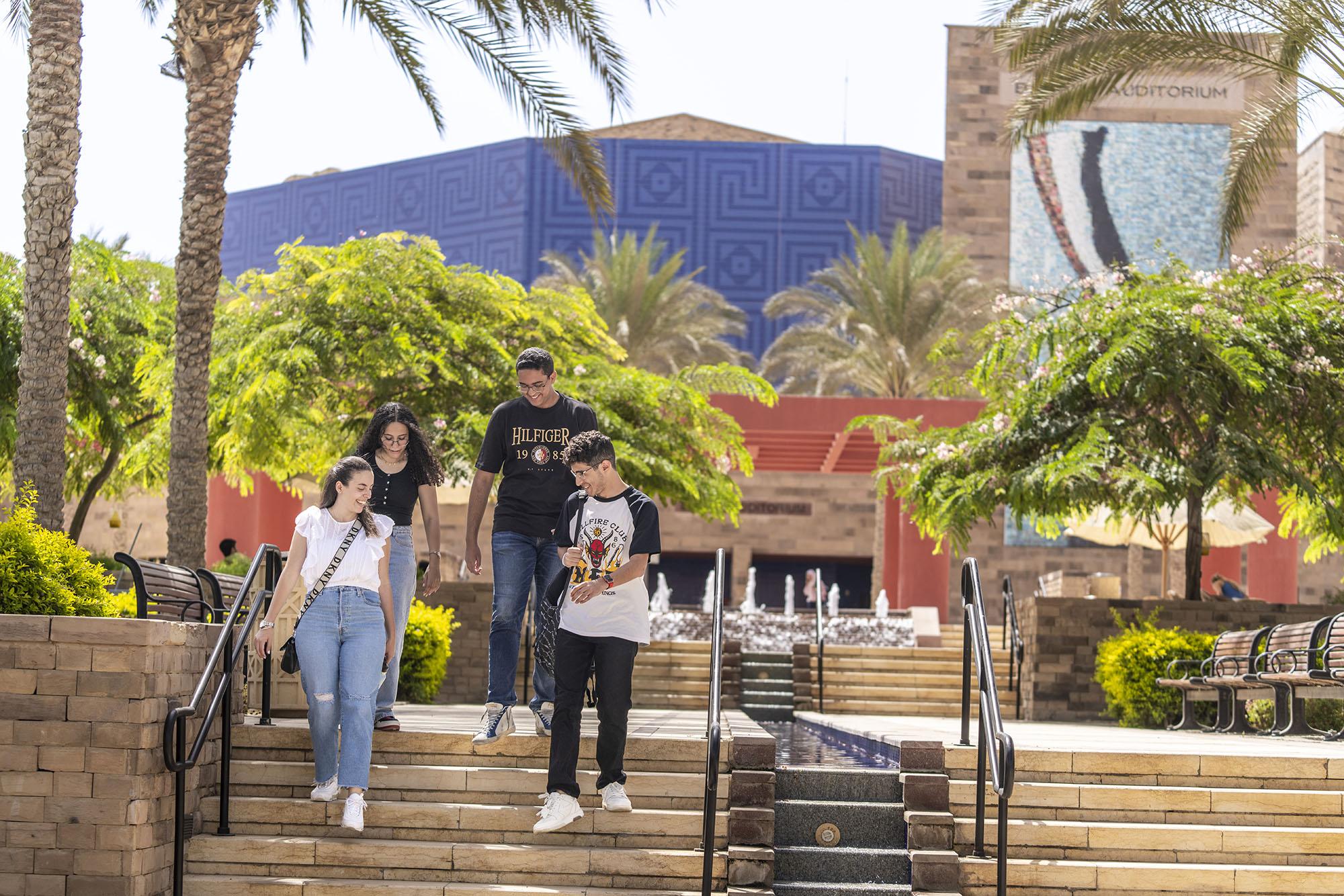 Girls and boys going down the stairs beside a fountain smiling