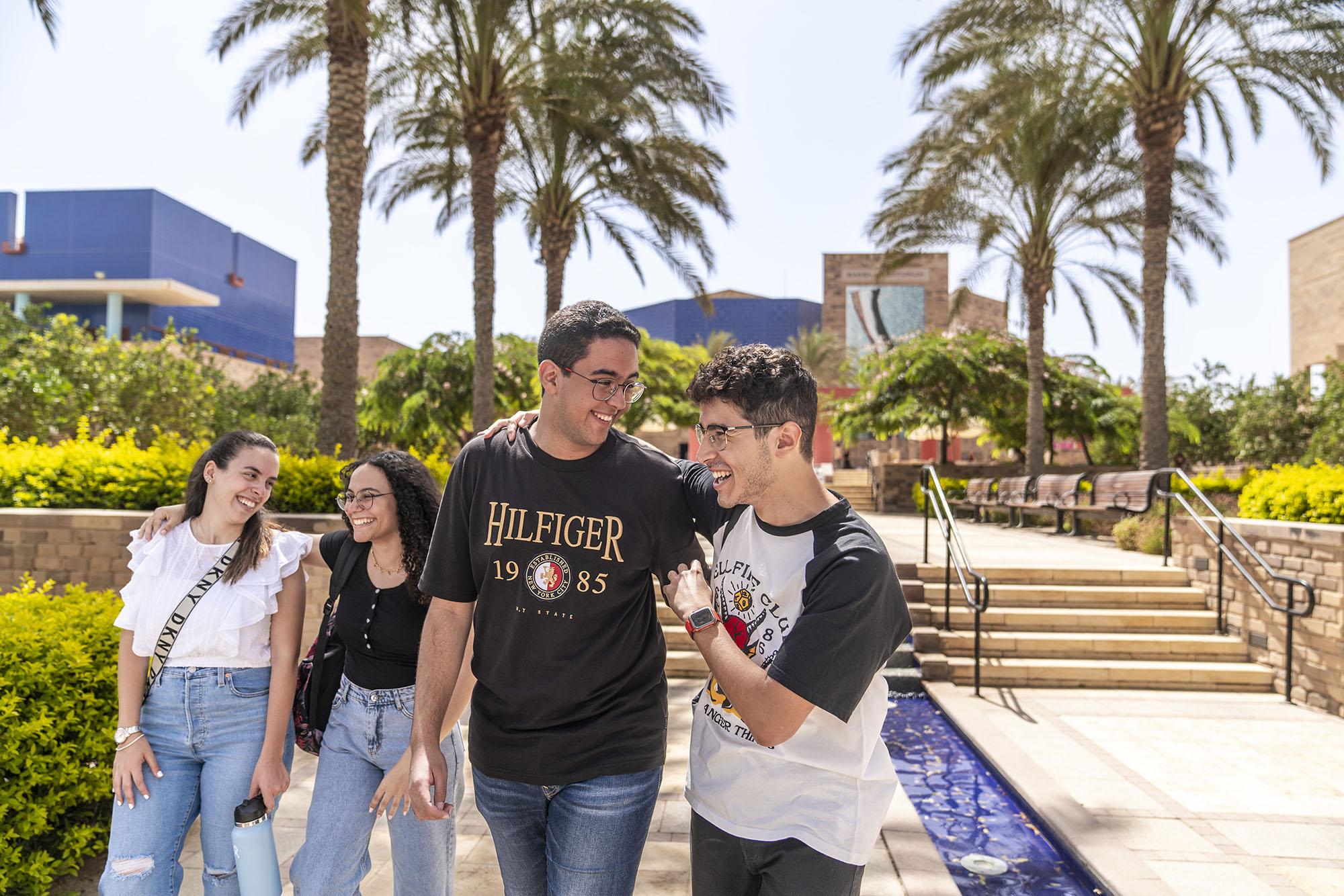 Girls and boys smiling walking on campus by the fountain smiling