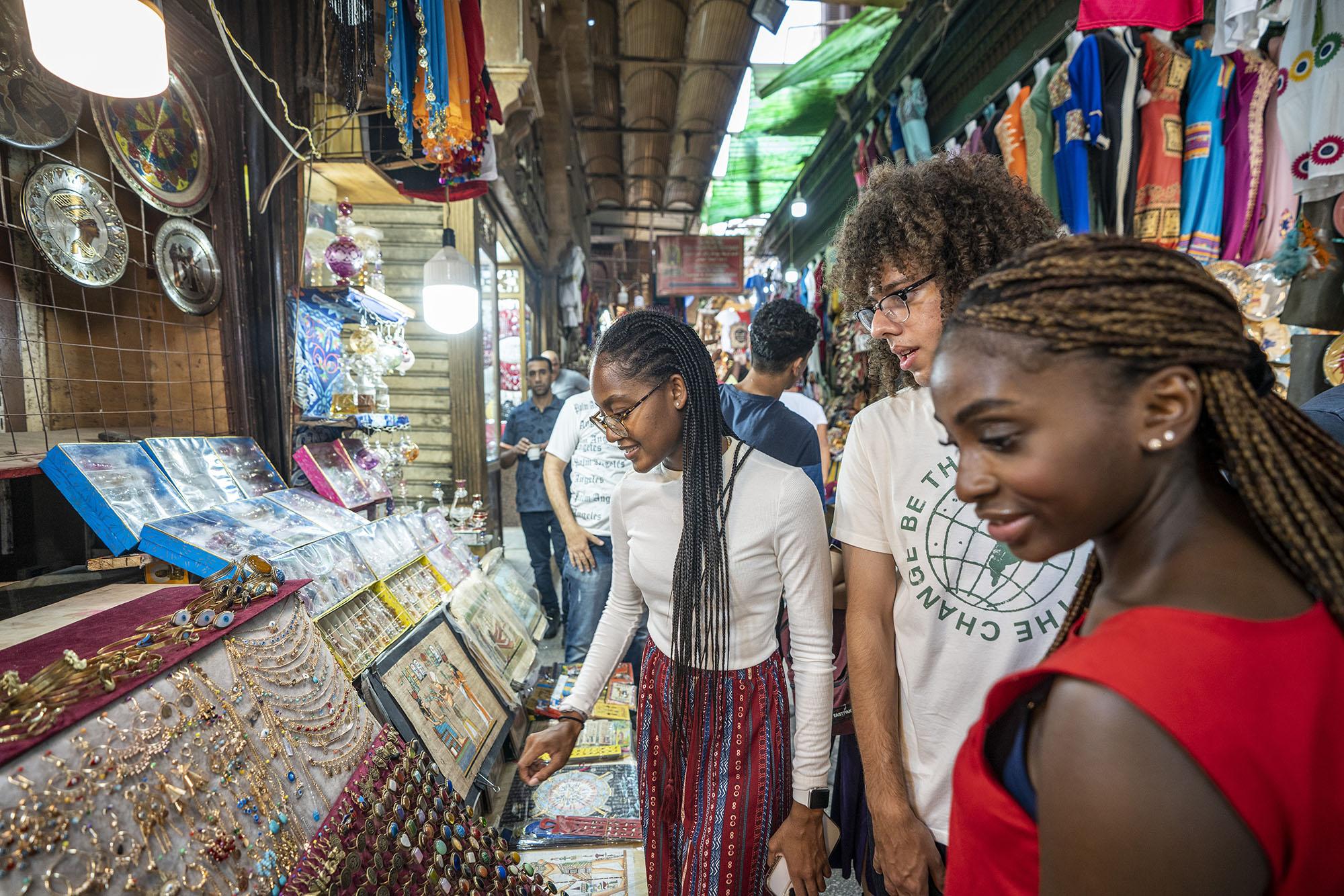 Two girls and a boy in an old market choosing jewelery
