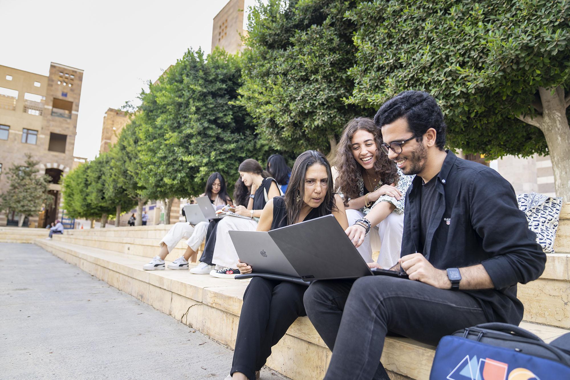 Instructor and students sitting on outside stairs of a building