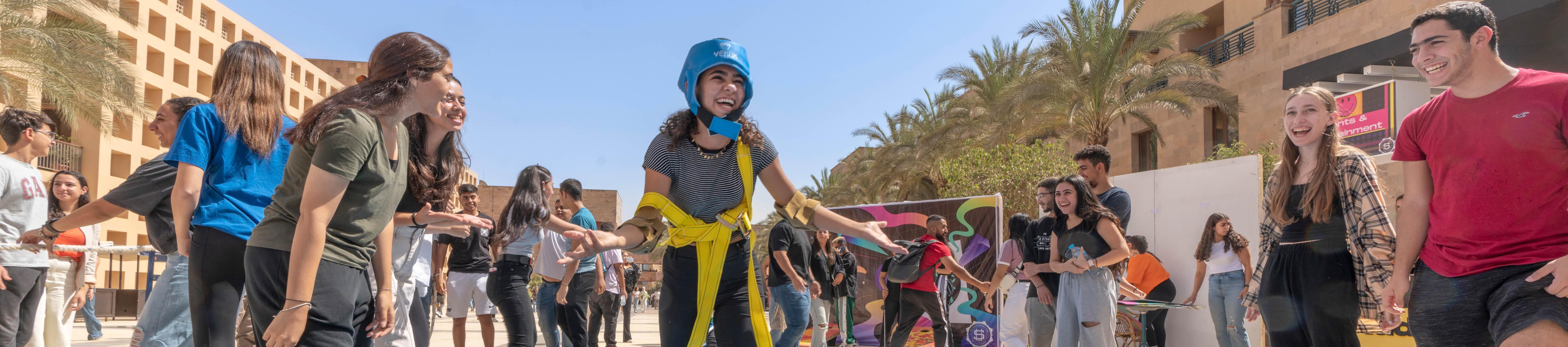a girl smiling and students playing games in the bartlett plaza