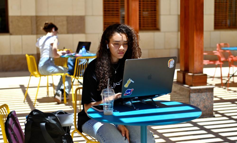 Girl sitting on her laptop outdoors