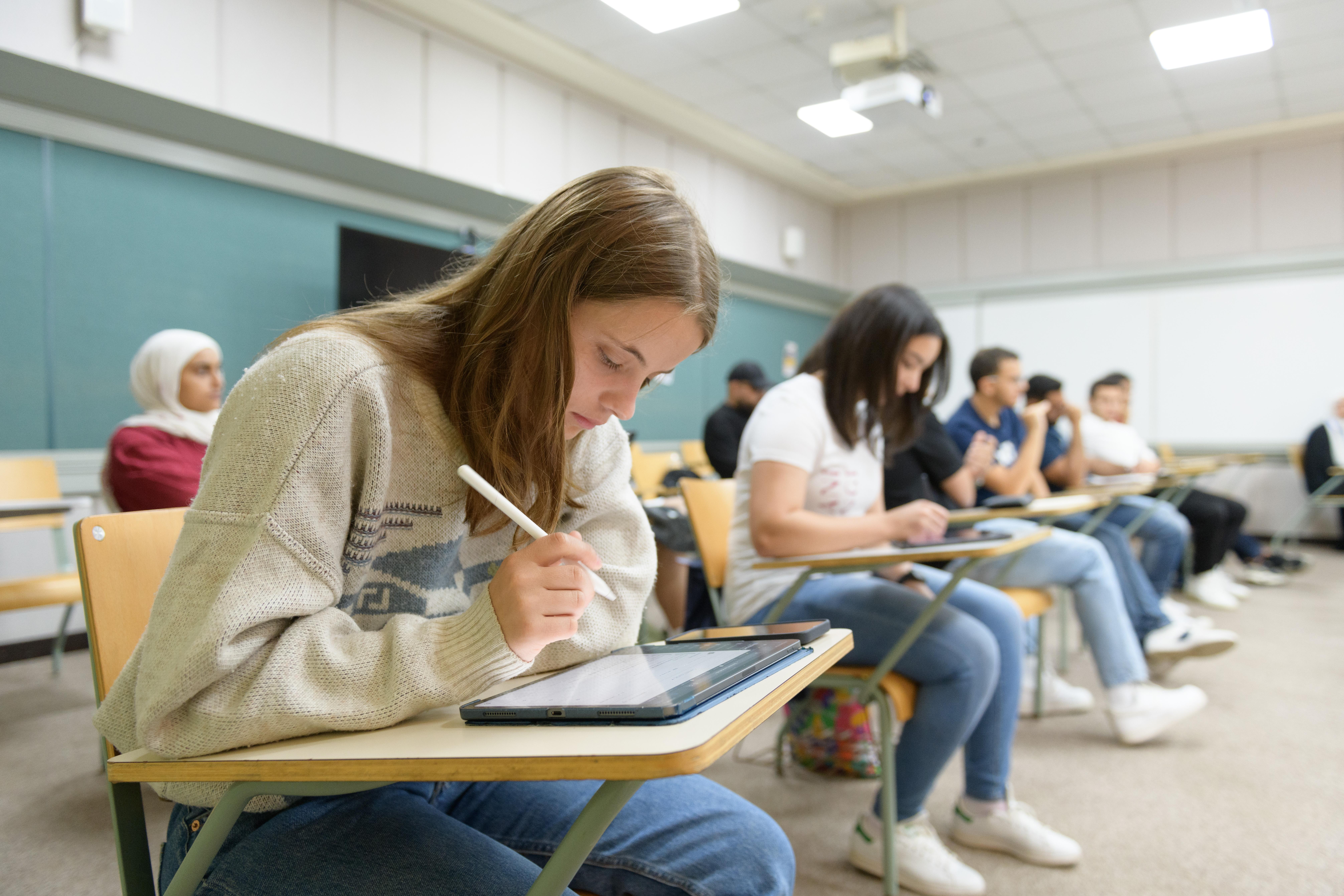 students in class writing on iPads