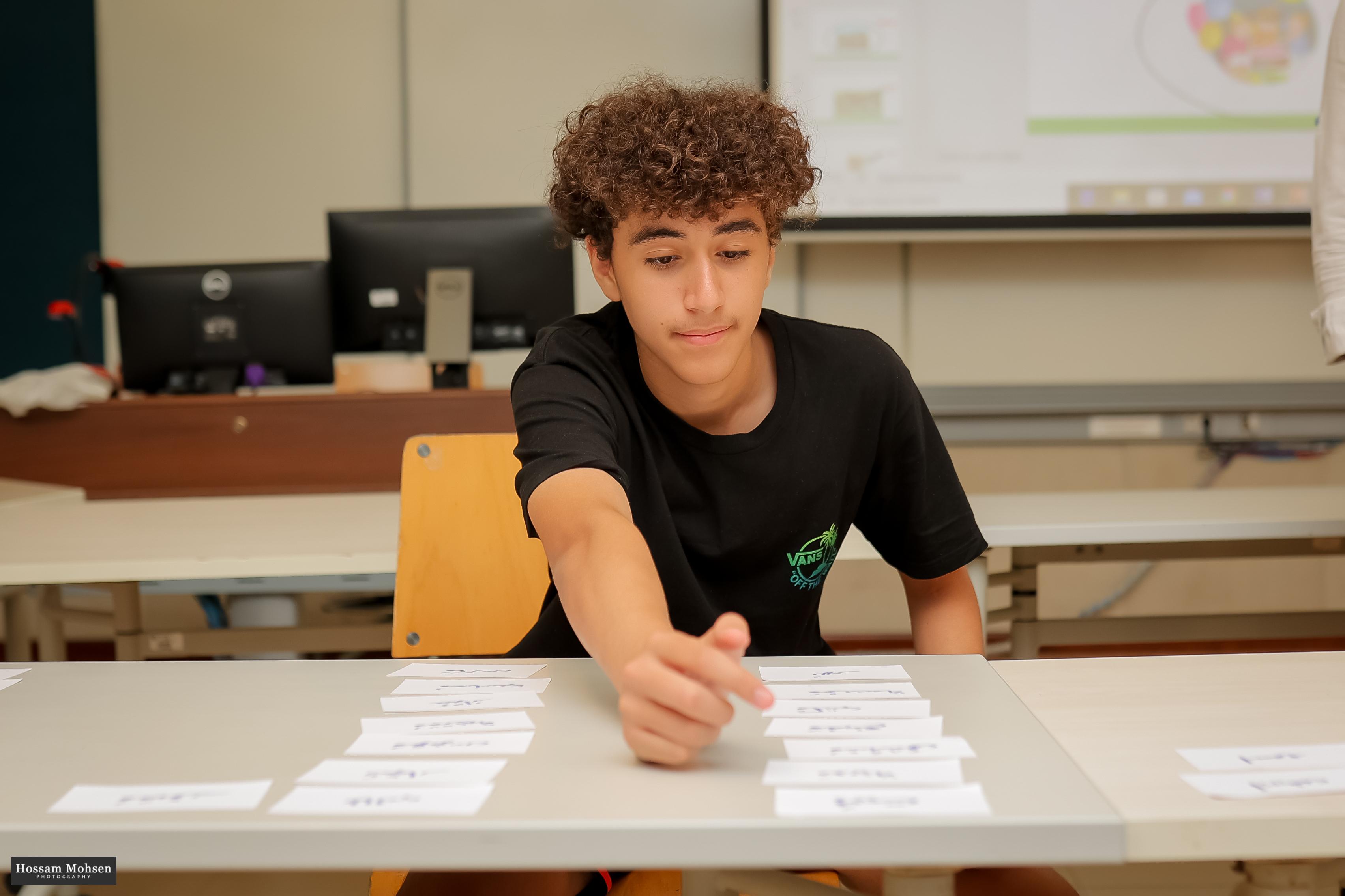 Student reading Arabic words from cards