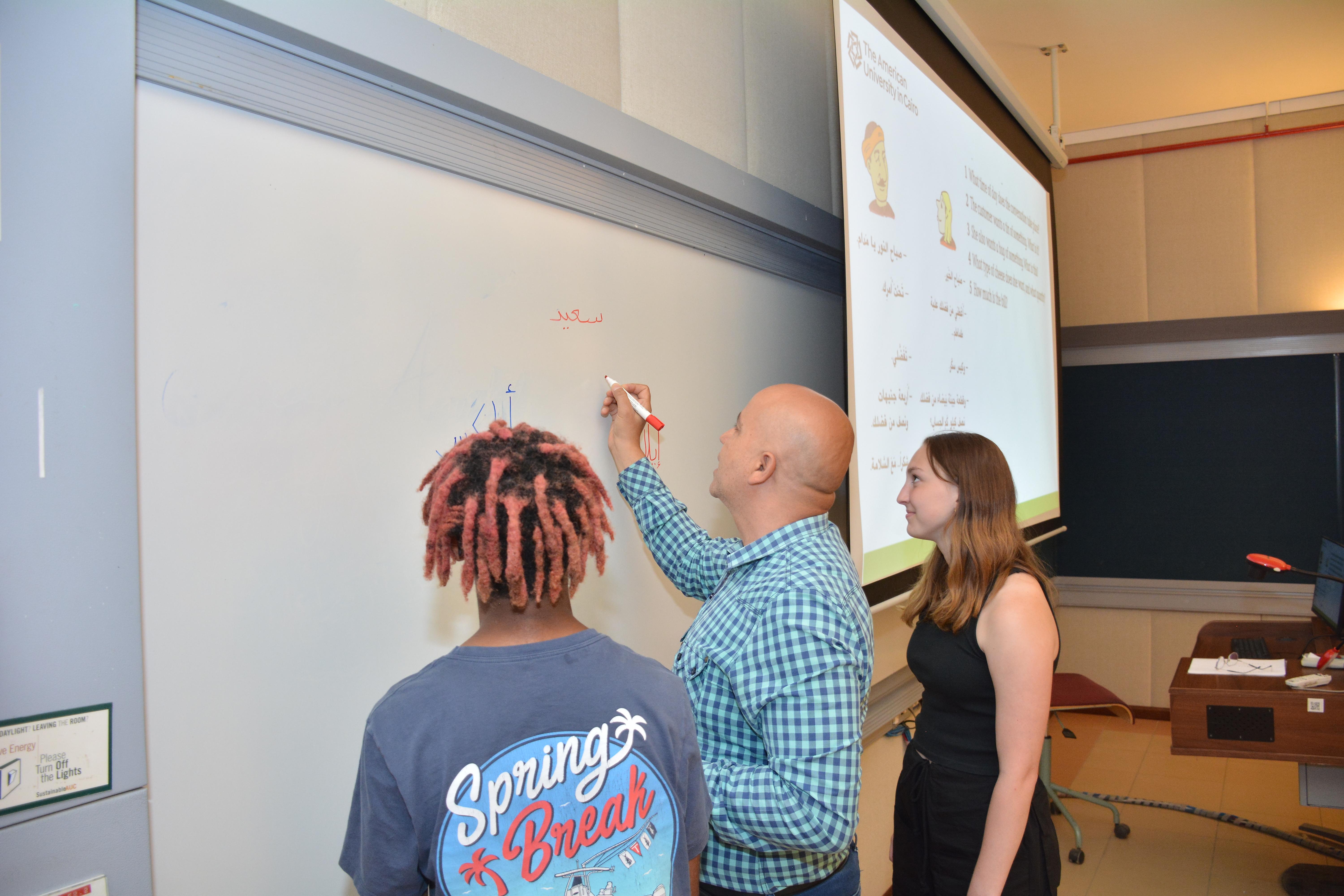 students and arabic professor in class wiring their names on the whiteboard