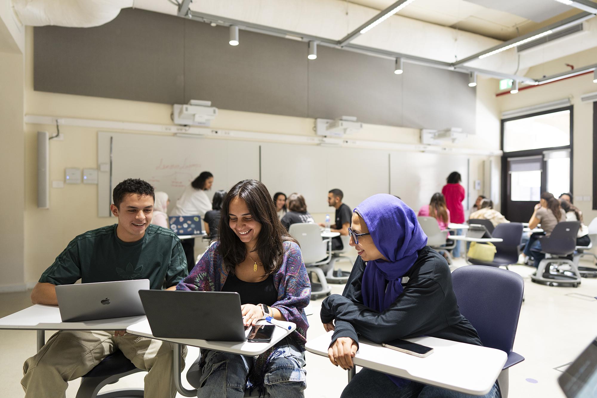 group of male and female students working on a class project on a laptop in class