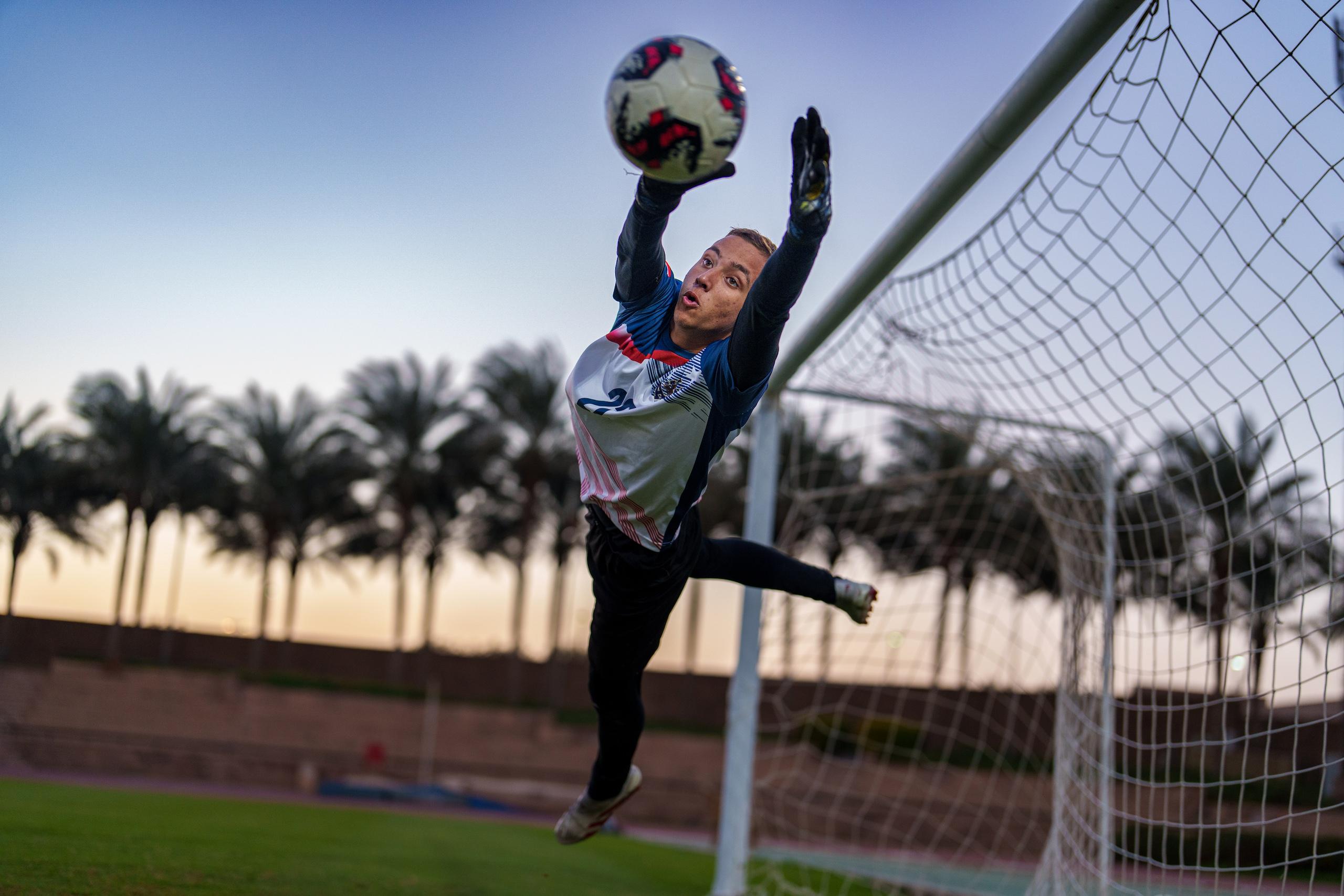 a goal keeper jumping to catch the ball