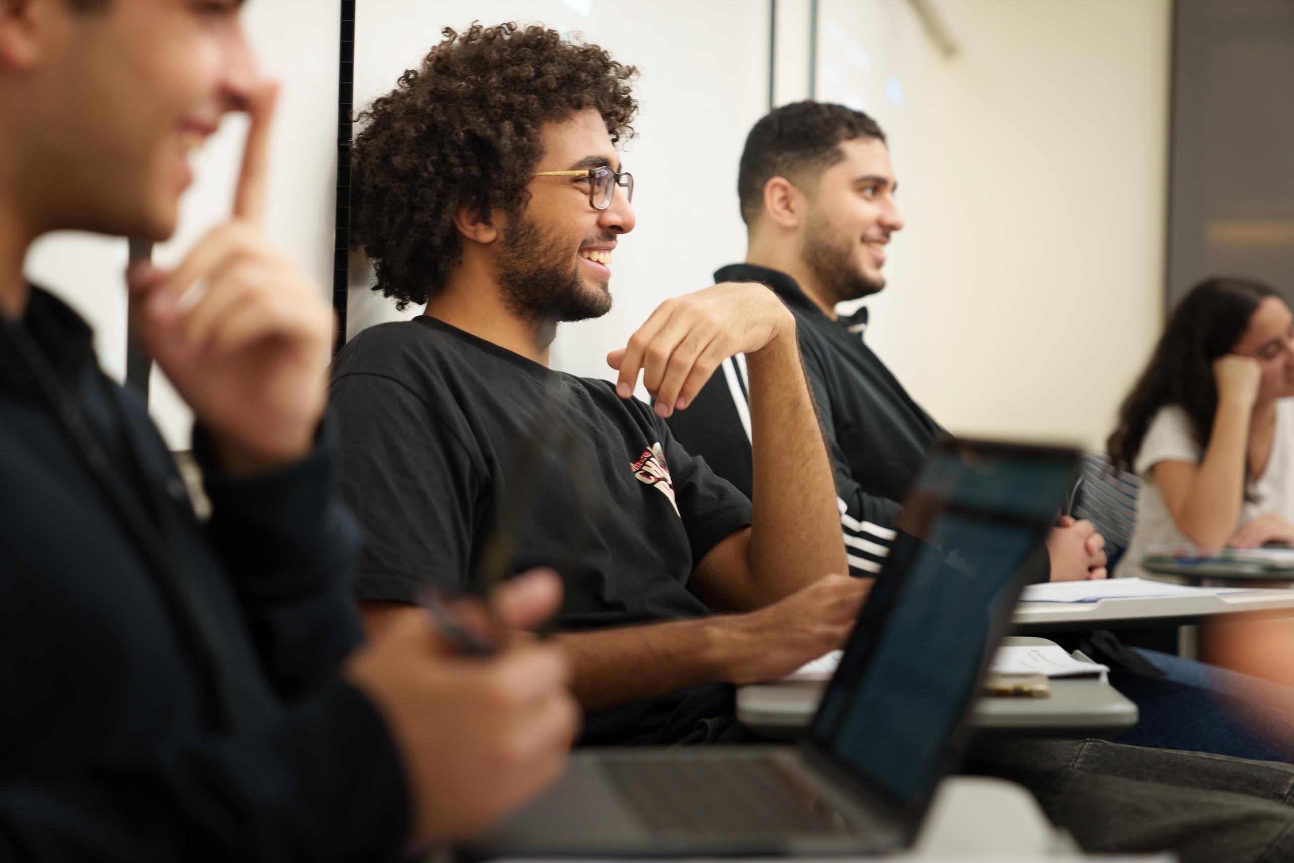 three boys wearing all black sitting in a classroom