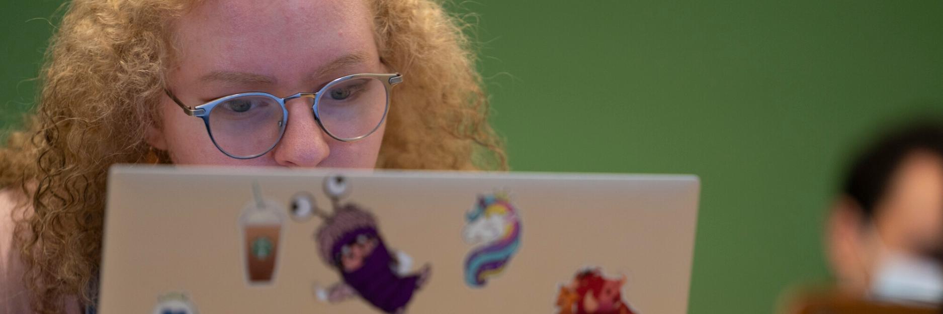 A girl with orange hair working on her laptop