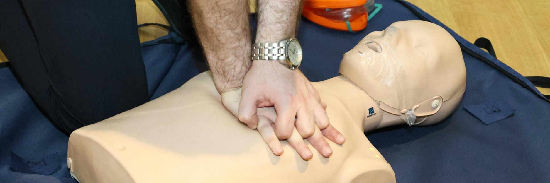 A man performing first aid on a manikin 