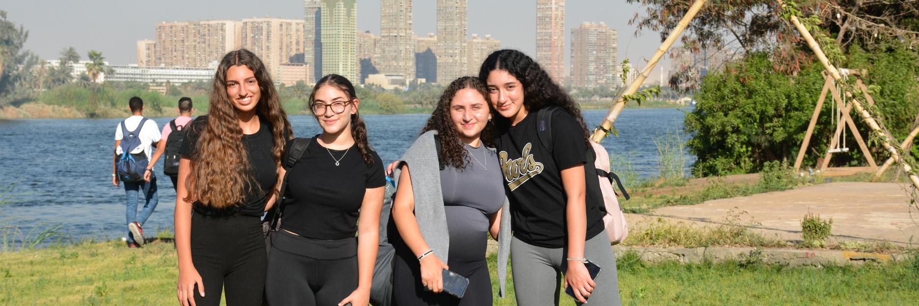 Four girls standing on grass and the Nile is behind them