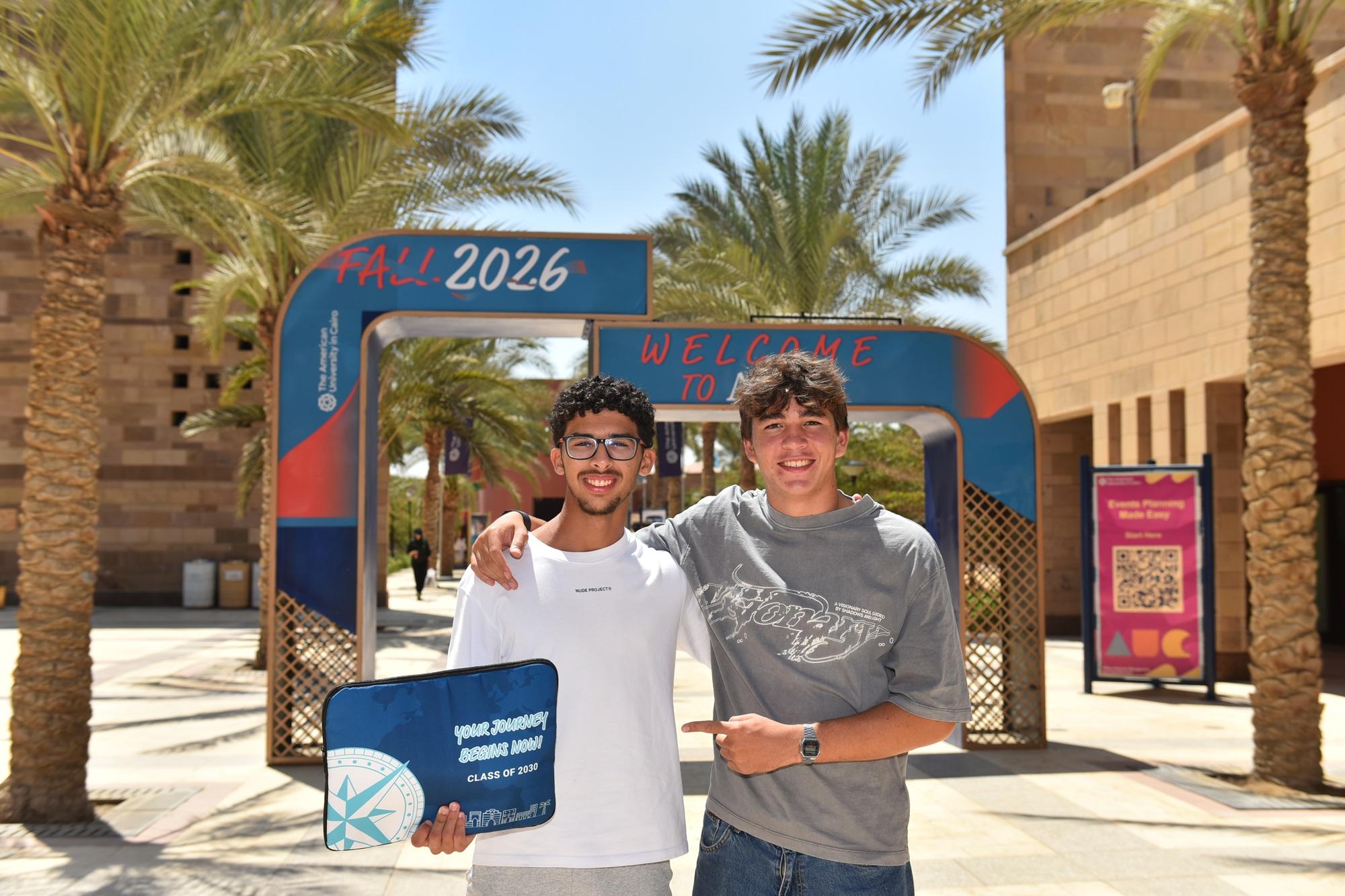 Two males are standing and smiling
