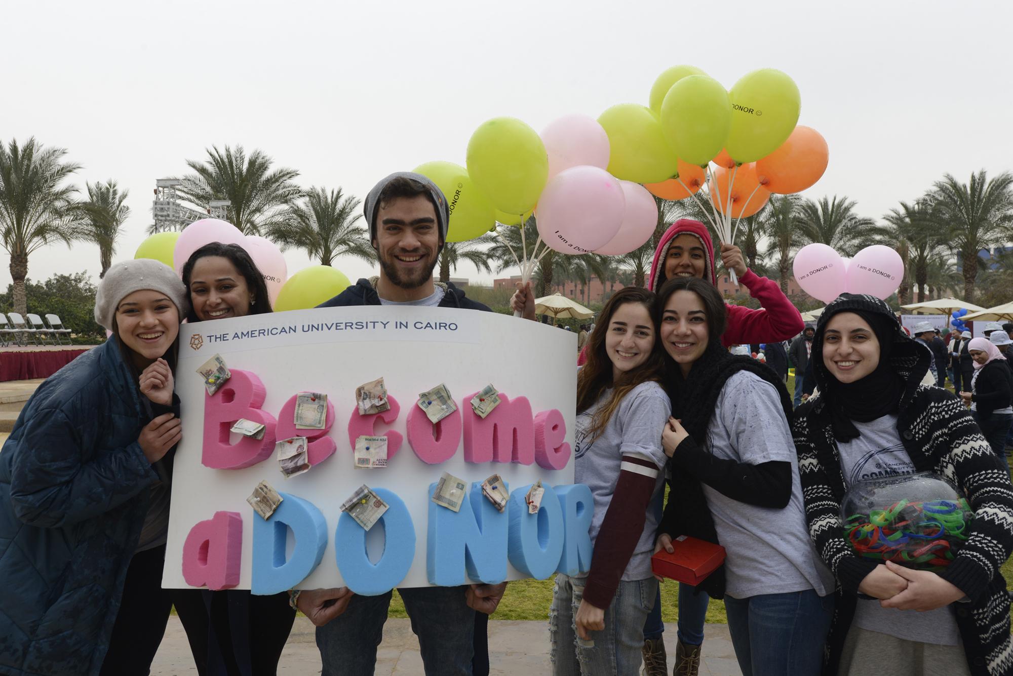 AUC community members holding banner saying "Become a donor" 