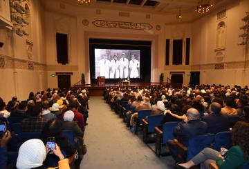 People sitting in a hall listening to people on stage